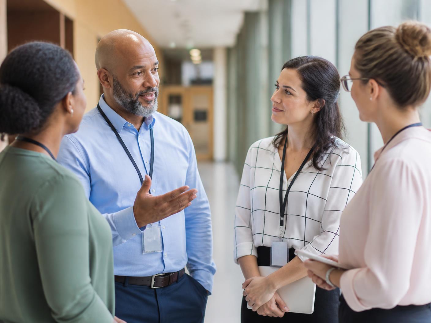 Educators and school staff having a supportive conversation in a school hallway